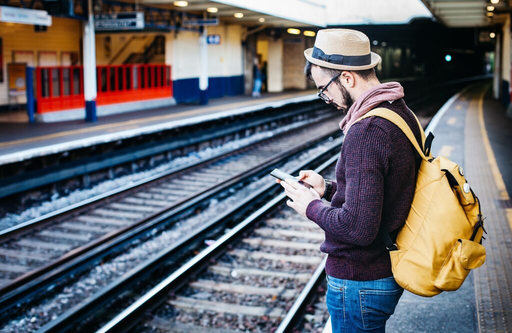 Viajero con mochila esperando el tren en una estación