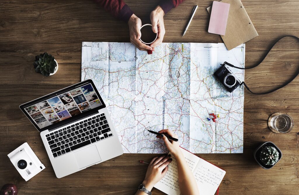 Personas planificando un viaje sobre un mapa con un portátil y una cámara